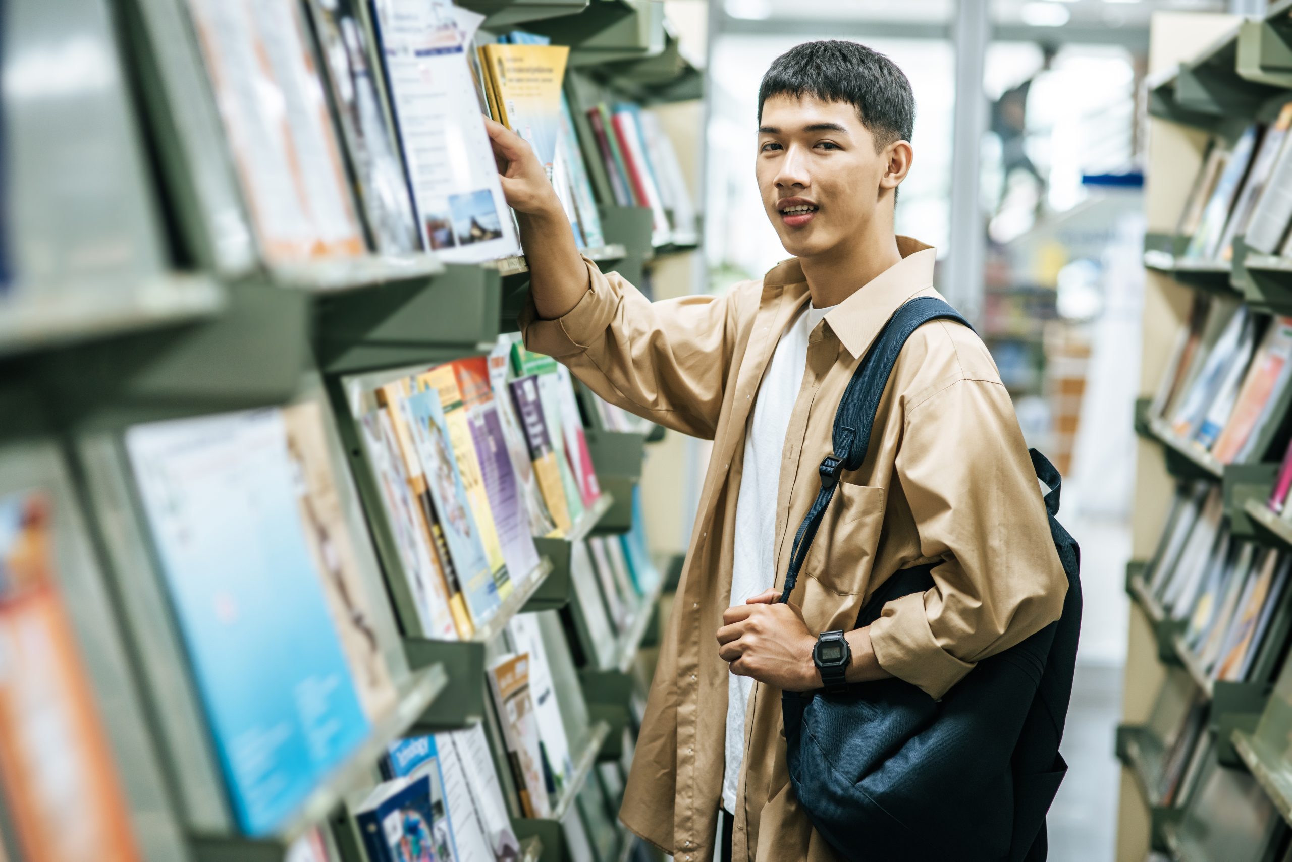 men carrying a backpack and searching for books in the library